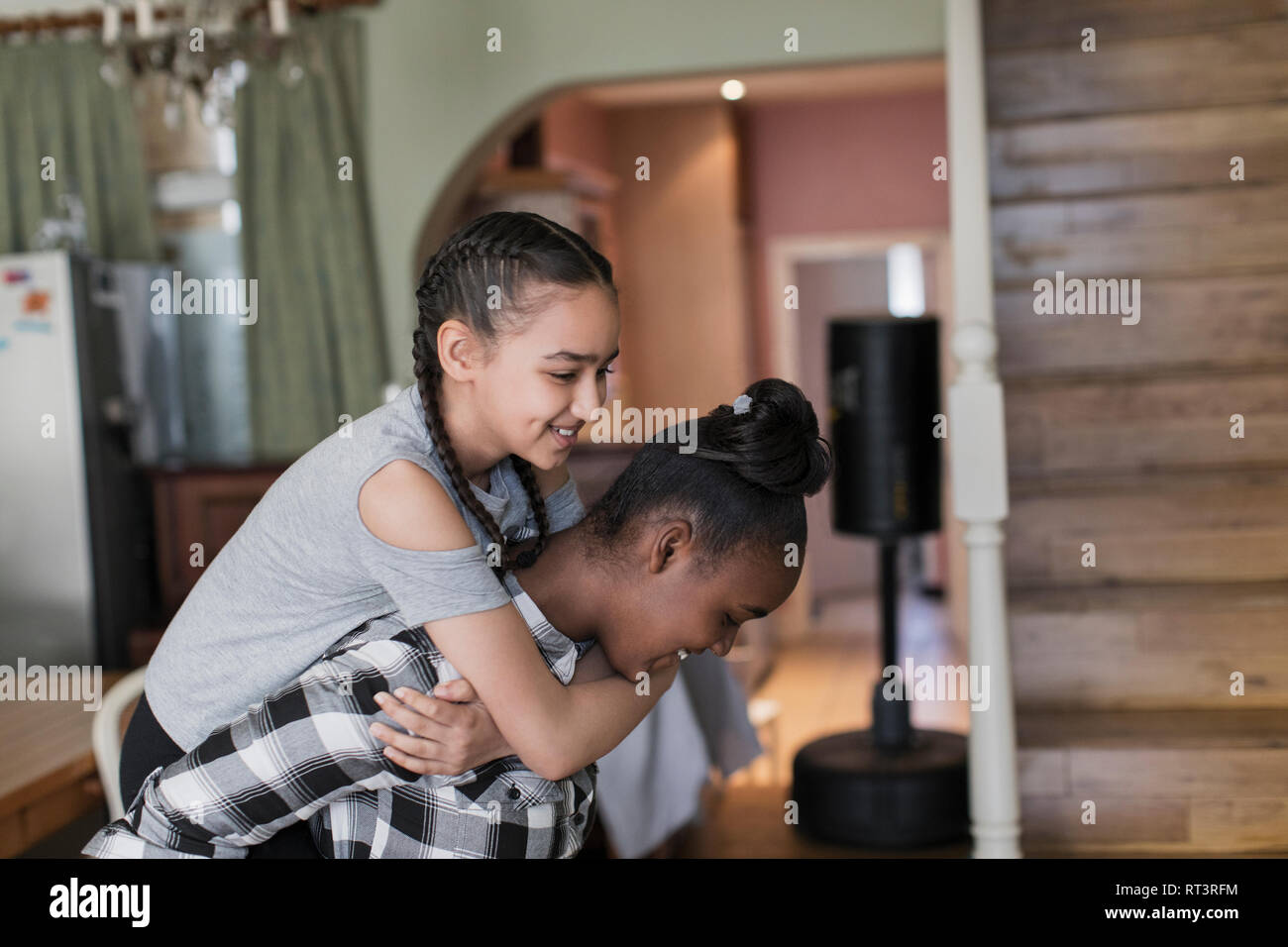 Giocoso tween girl amici piggybacking Foto Stock