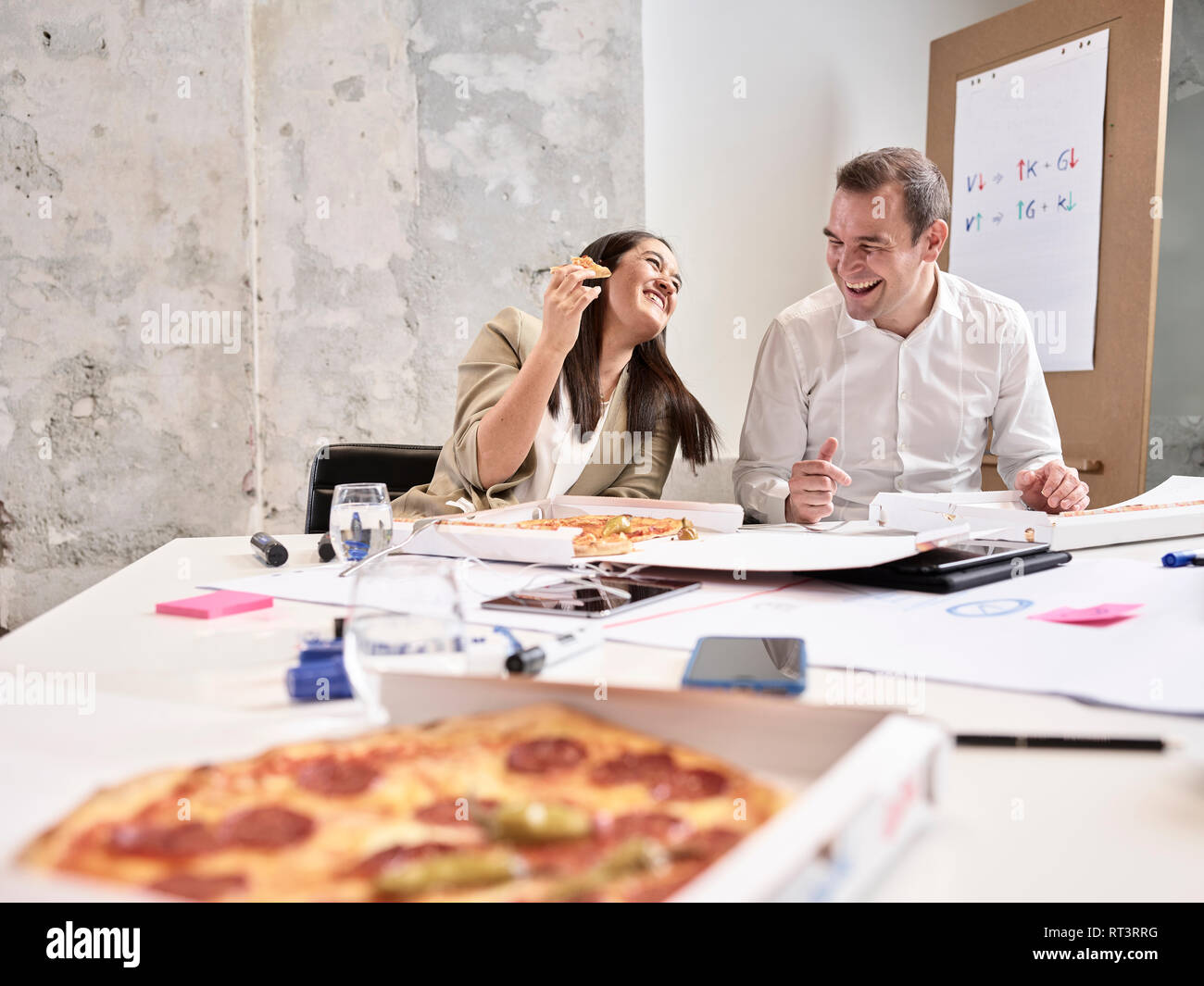 Ridere i colleghi avente la pausa pranzo con pizza in sala conferenze Foto Stock