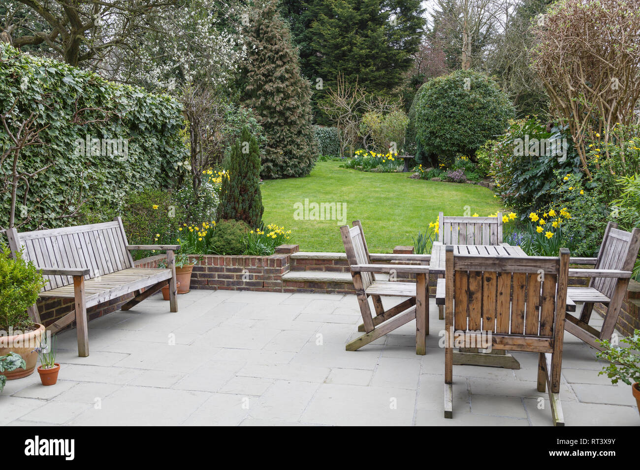 Panca in legno, tavolo e sedie sul patio in una Londra giardino suburbano Foto Stock