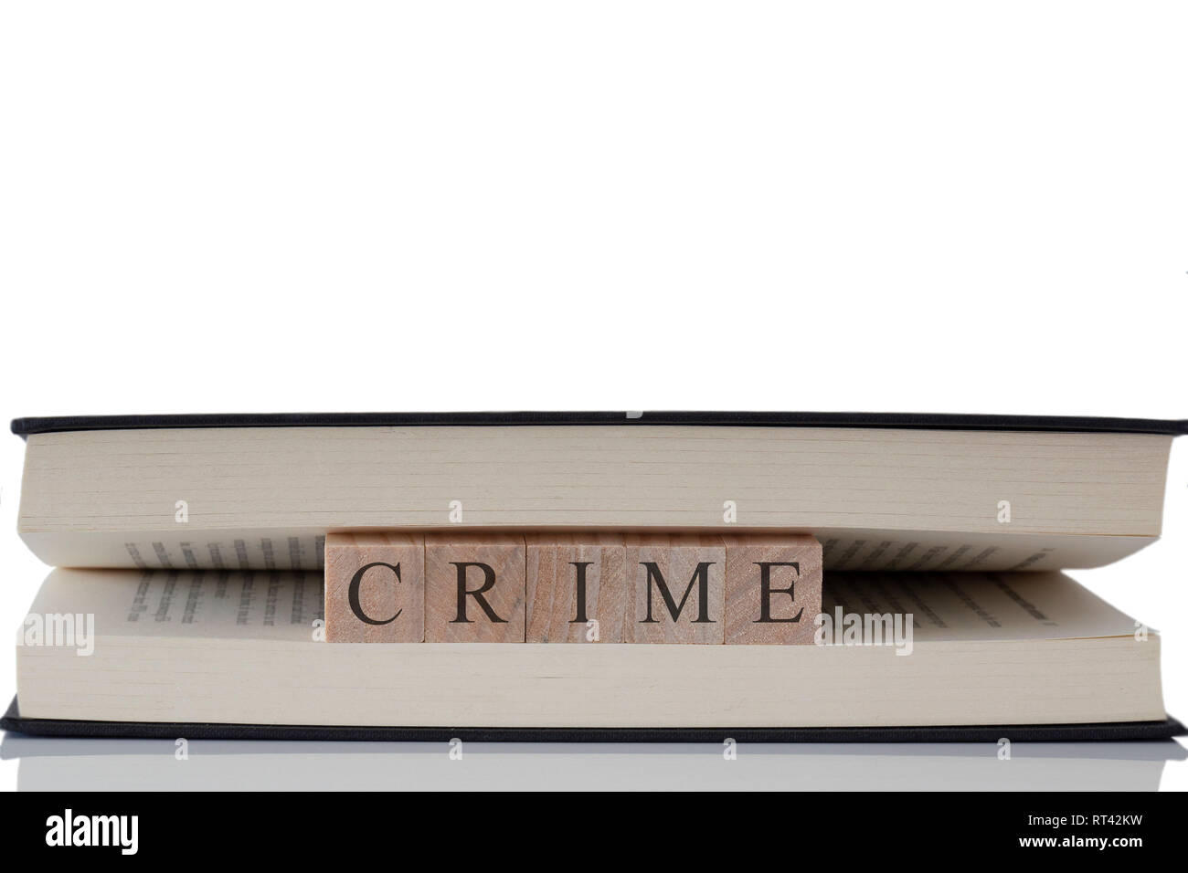 La criminalità scritto su blocchi di legno all'interno di un libro isolato su uno sfondo bianco con la riflessione Foto Stock