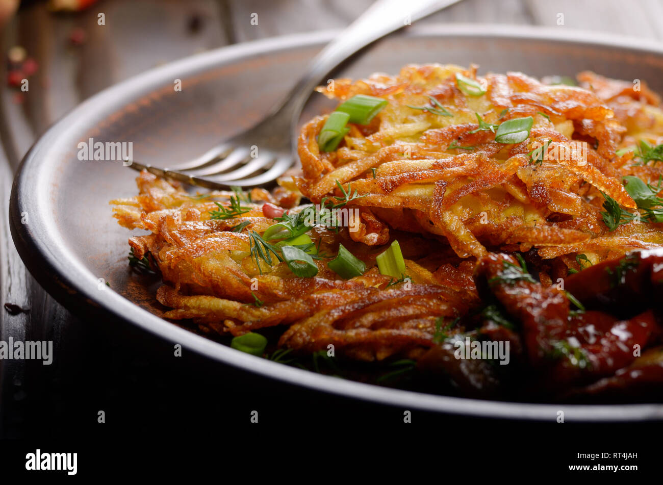 Primo piano a in casa gustose frittelle di patate nel piatto di argilla con pomodori secchi Foto Stock