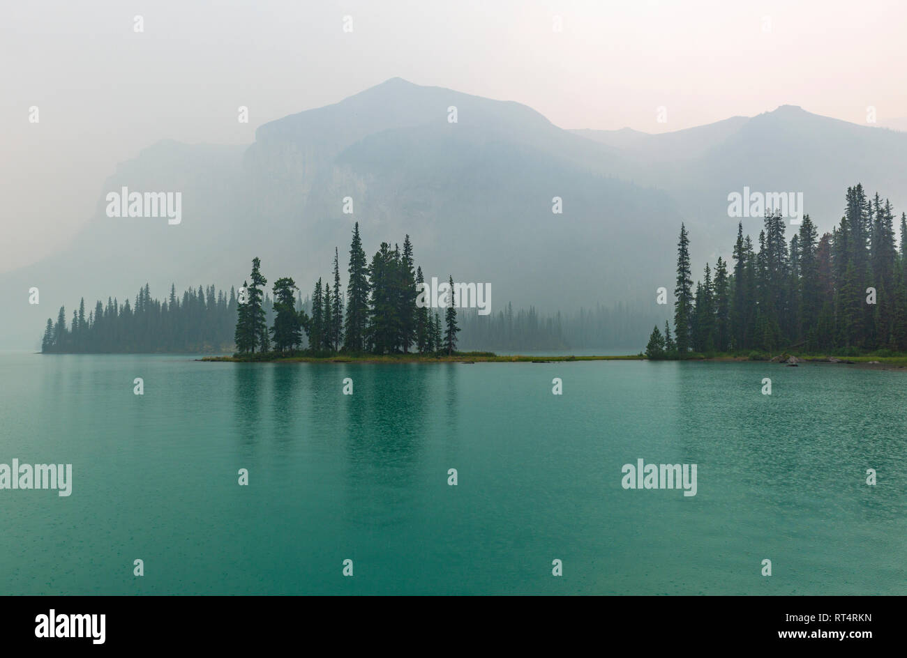 La riflessione dell'inafferrabile e magnifica isola di spirito nella nebbia, situato all'interno del Lago Maligne nel Parco Nazionale di Jasper, Alberta, Canada. Foto Stock