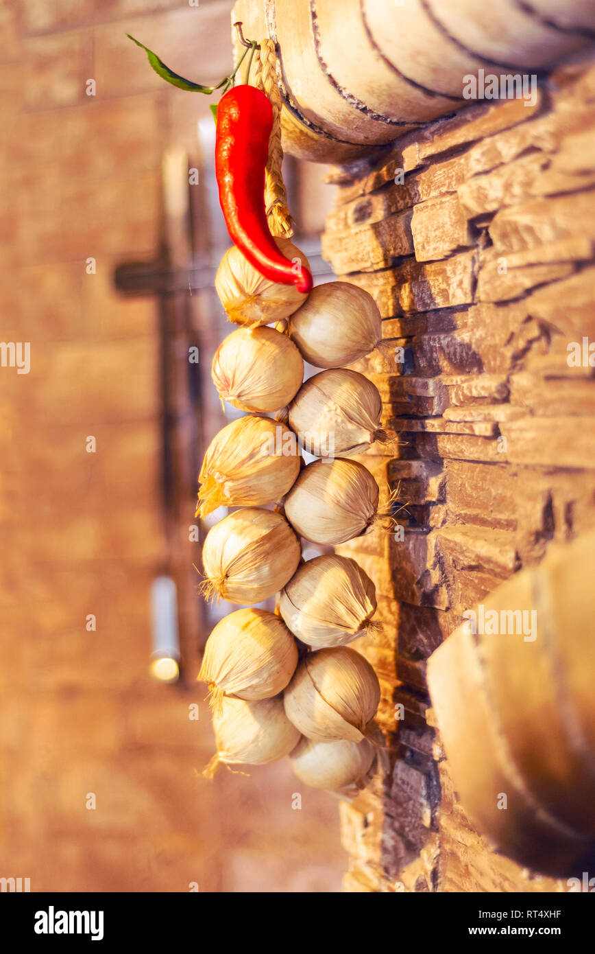 Peperoncino rosso piccante fasci di aglio appeso alla parete di texture Foto Stock