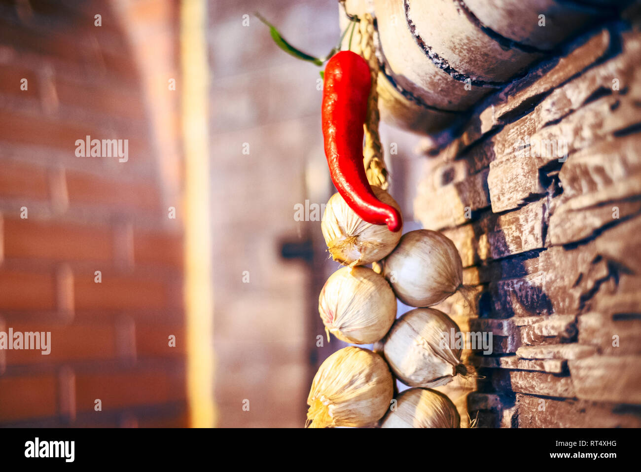 Peperoncino rosso piccante fasci di aglio appeso alla parete di texture Foto Stock