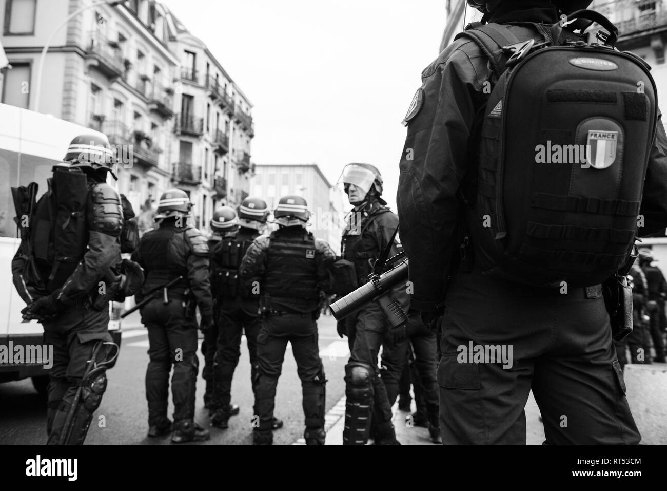 Strasburgo, Francia - 8 dicembre 2018: vista posteriore equipaggiato con pistole di funzionari di polizia che fissano la zona anteriore del Giallo giubbotti di manifestanti di movimento sul Quai des Bateliers street Foto Stock