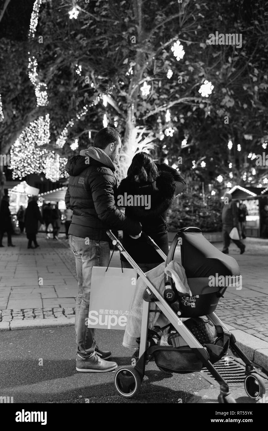 Strasburgo, Francia - Nov 29, 2017: immagine in bianco e nero di coppia giovane con la carrozzina passeggino ammirando la illuminazione di Natale e le decorazioni del magico Mercatino di Natale di Strasburgo, Alsazia durante la notte Foto Stock