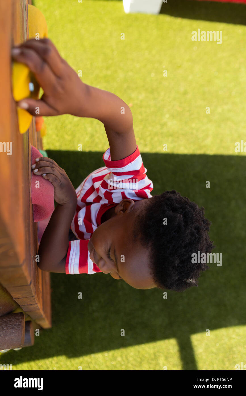 Scolaro salendo una parete nella scuola parco giochi Foto Stock