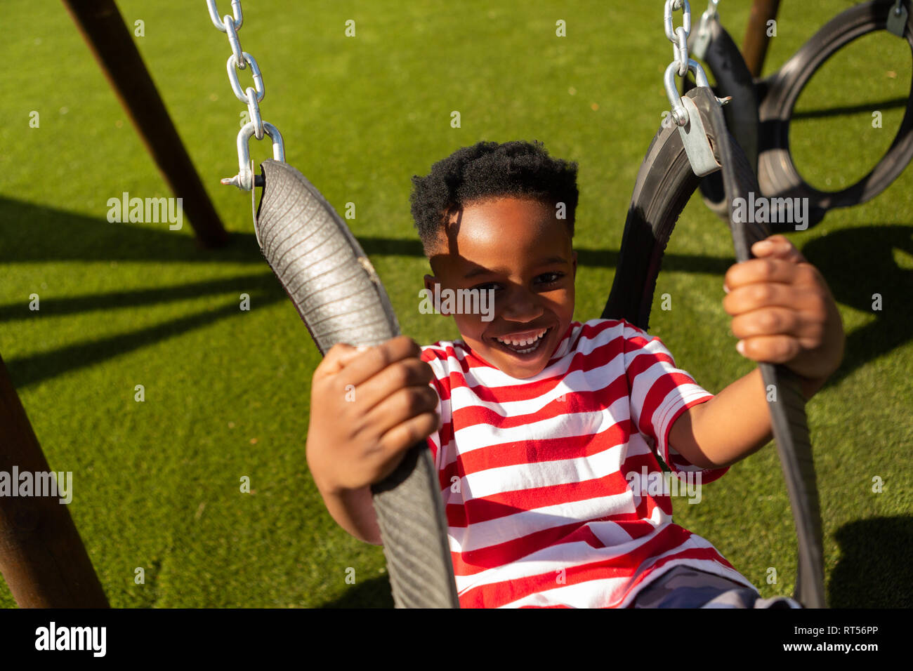 Scolaro giocando su una oscillazione a scuola parco giochi Foto Stock