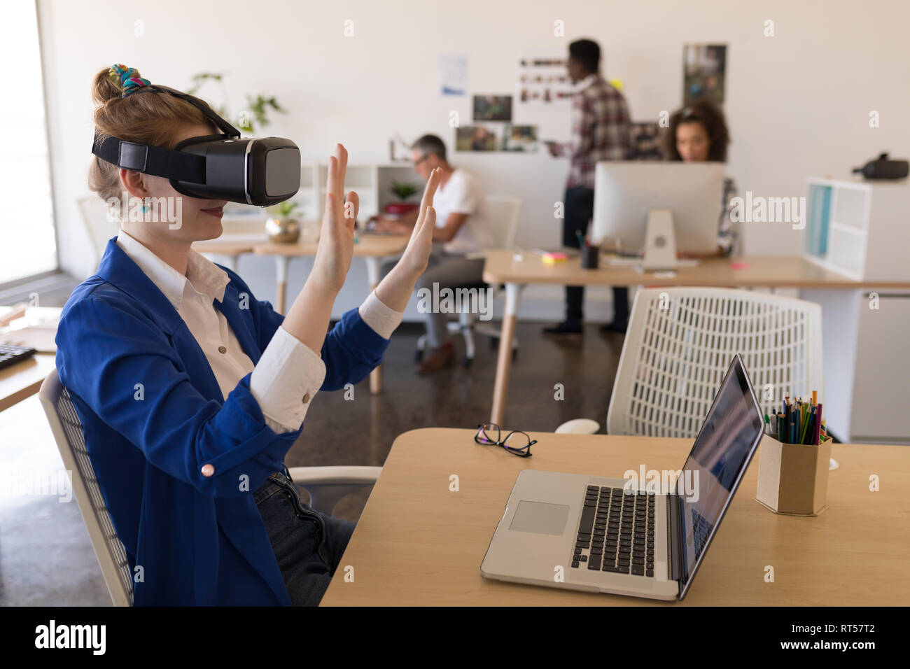 Imprenditrice utilizzando la realtà virtuale auricolare a scrivania Foto Stock