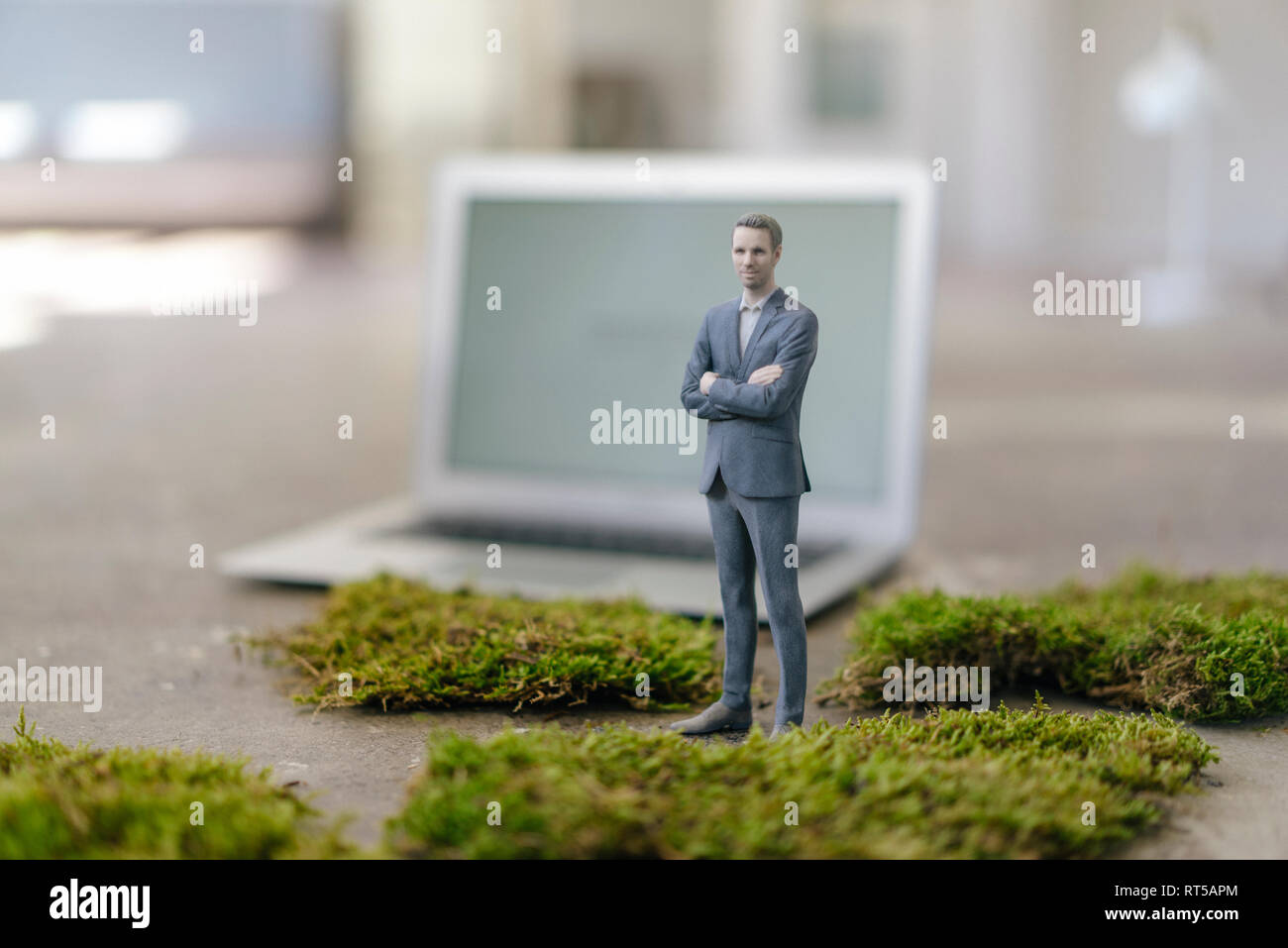 Imprenditore figurina con il computer portatile in piedi sul verde muschio Foto Stock