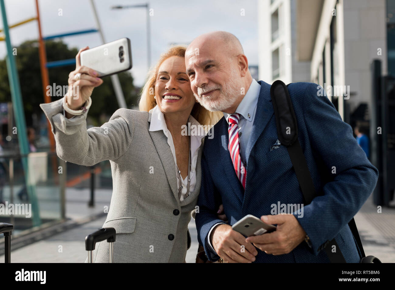 Imprenditore Senior e imprenditrice con bagaglio prendendo un selfie nella città Foto Stock