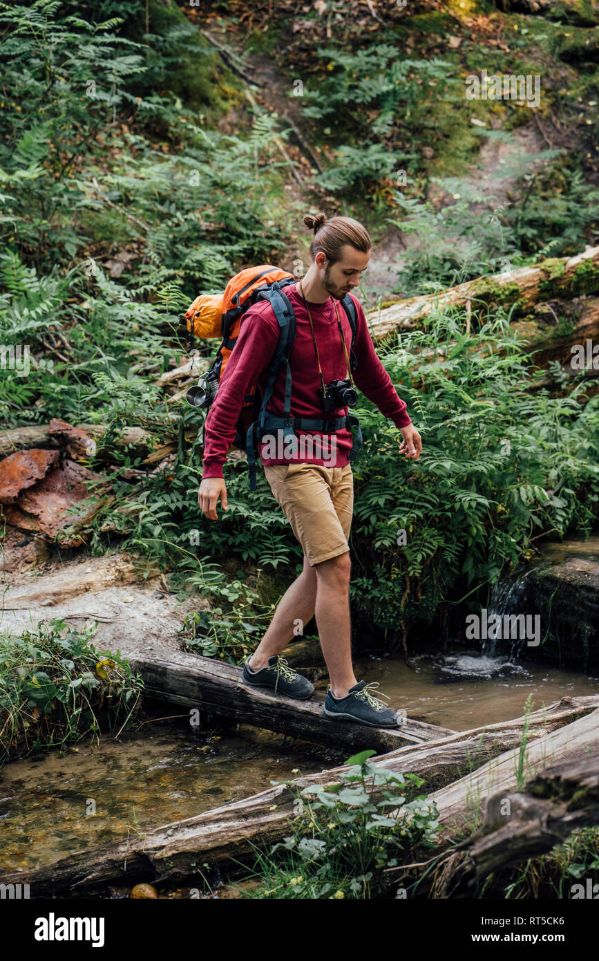 Giovane escursionista con zaino acqua di attraversamento della foresta Foto Stock