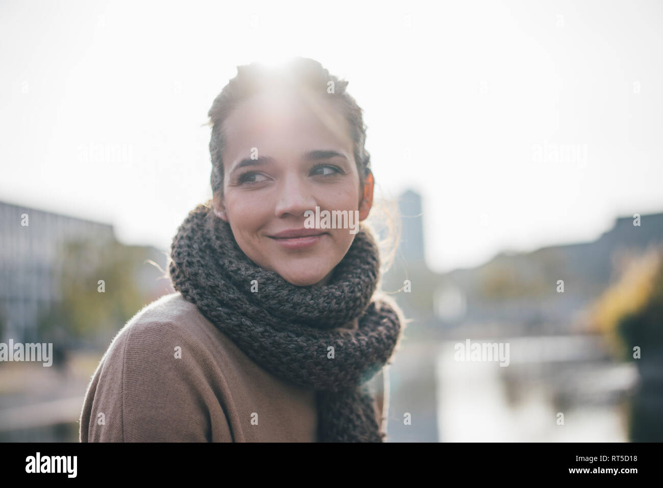 Ritratto di donna sorridente indossando sciarpa a retroilluminazione Foto Stock