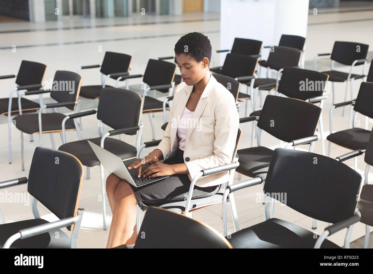 Imprenditrice seduti su una sedia e utilizzando computer portatile nella hall Foto Stock