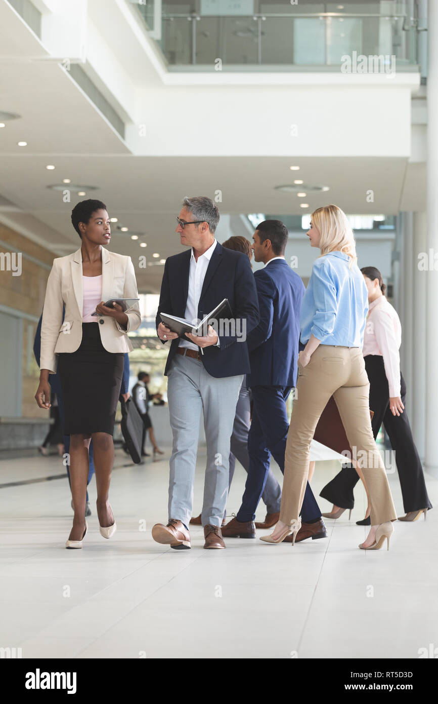 Diverse persone di affari interagire gli uni con gli altri mentre si cammina nella lobby e office Foto Stock