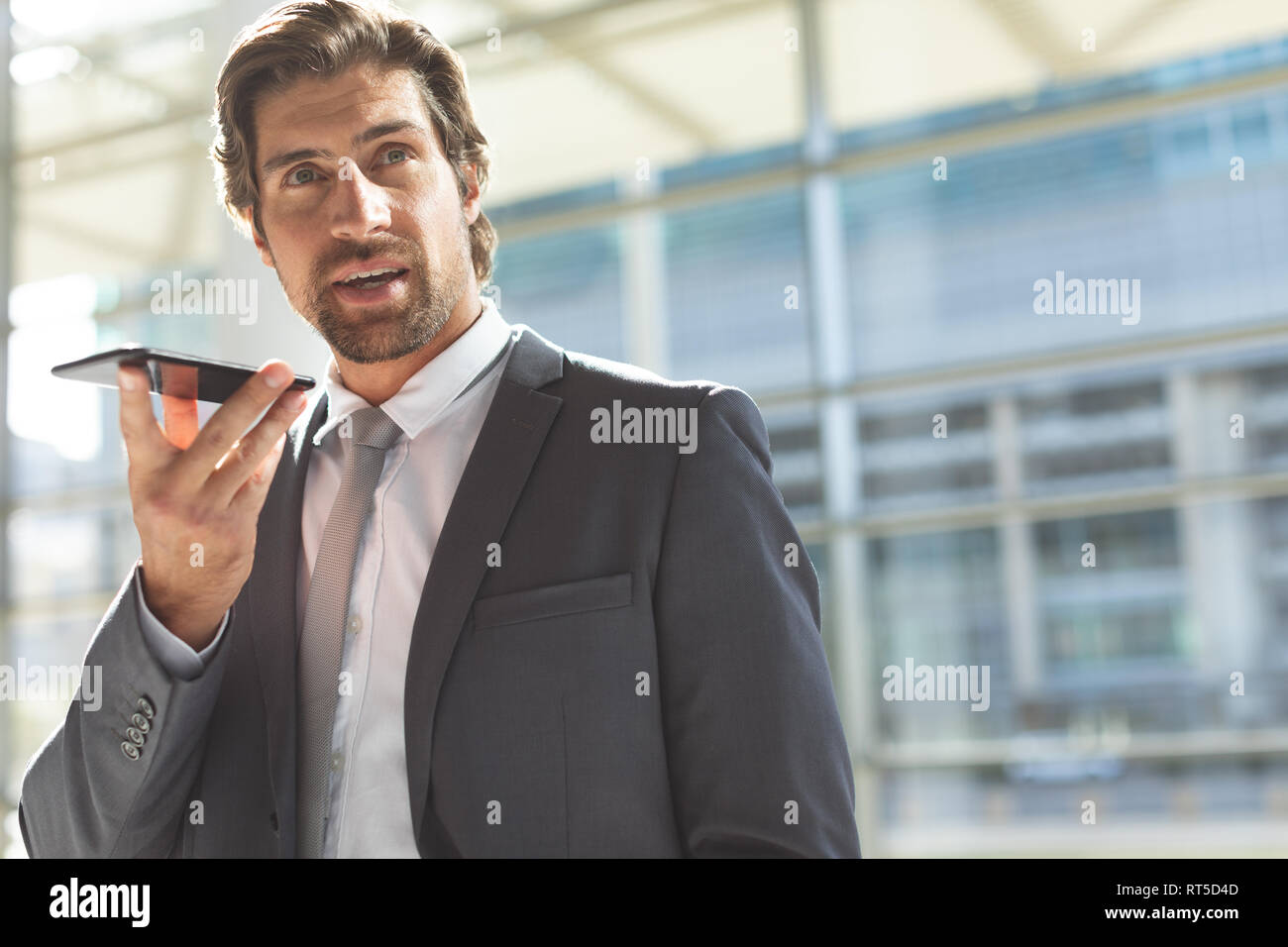 Imprenditore parlando al telefono cellulare nella lobby e office Foto Stock