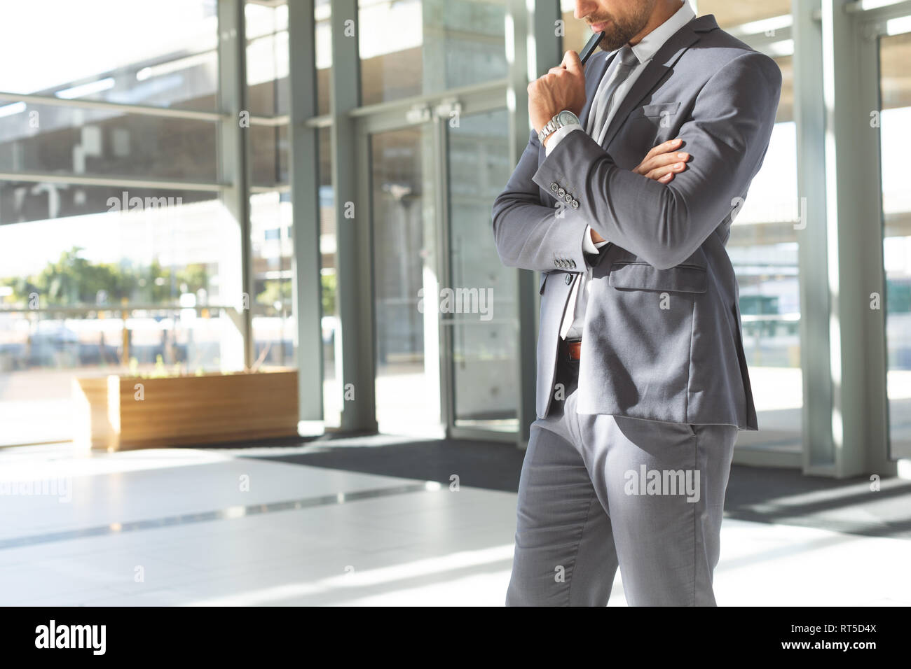Considerato giovane imprenditore a testa in giù sul suo telefono cellulare in piedi nella lobby e office Foto Stock