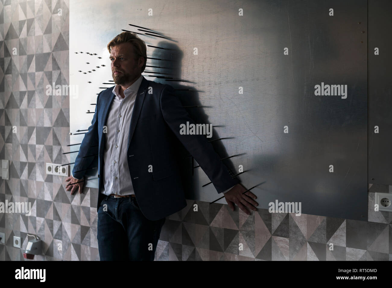 Imprenditore standiing nella sala riunioni con il dorso di un magnete a parete, incorniciato dalle frecce Foto Stock