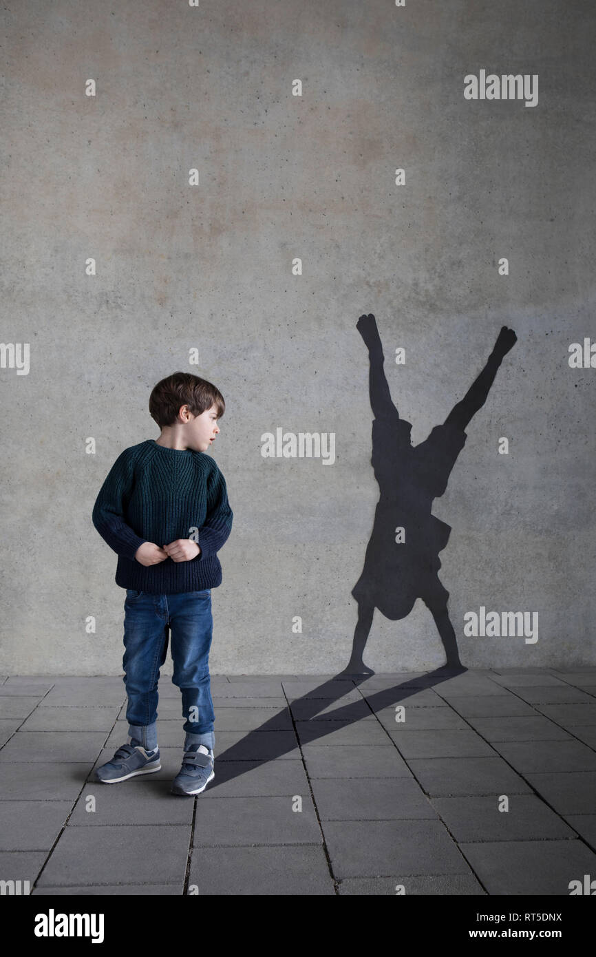 Germania, Duesseldorf, Little Boy guardando all ombra di Duesseldorf's cartwheeler sulla parete in background Foto Stock