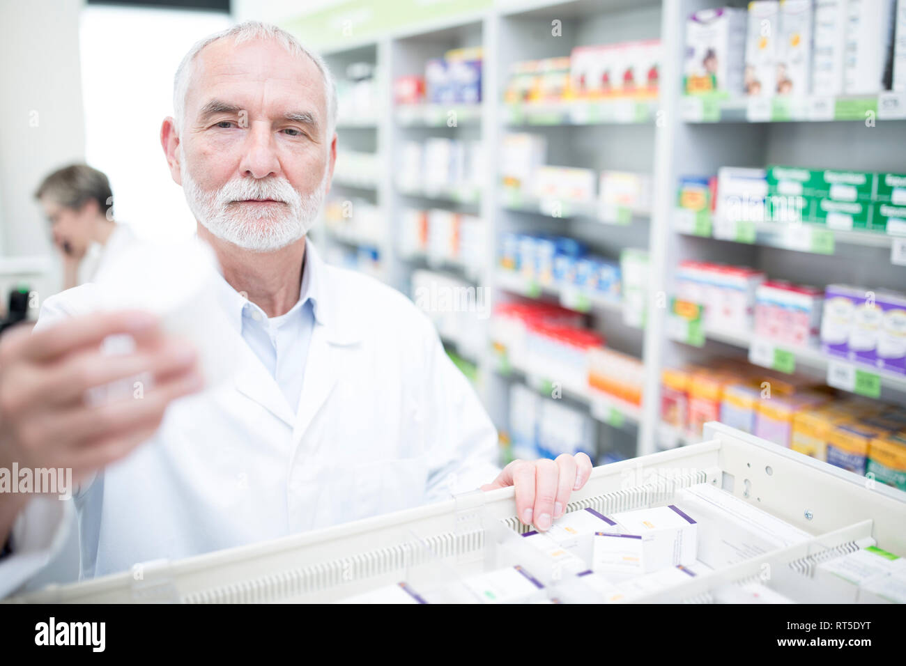 Il farmacista di prendere la medicina dal cabinet in farmacia Foto Stock