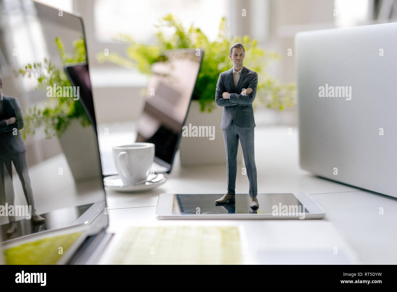 Imprenditore figurina in piedi su una scrivania con i dispositivi mobili e una tazza di caffè Foto Stock