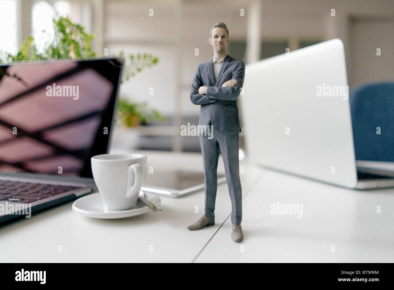 Imprenditore figurina in piedi su una scrivania con i dispositivi mobili e una tazza di caffè Foto Stock