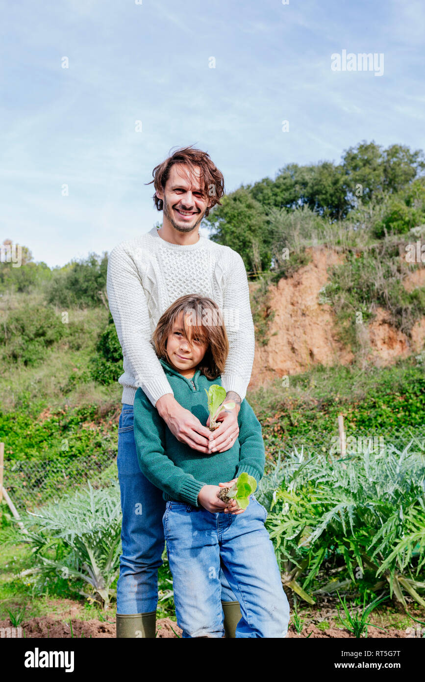 Padre e figlio azienda germogli di lattuga in un orto Foto Stock