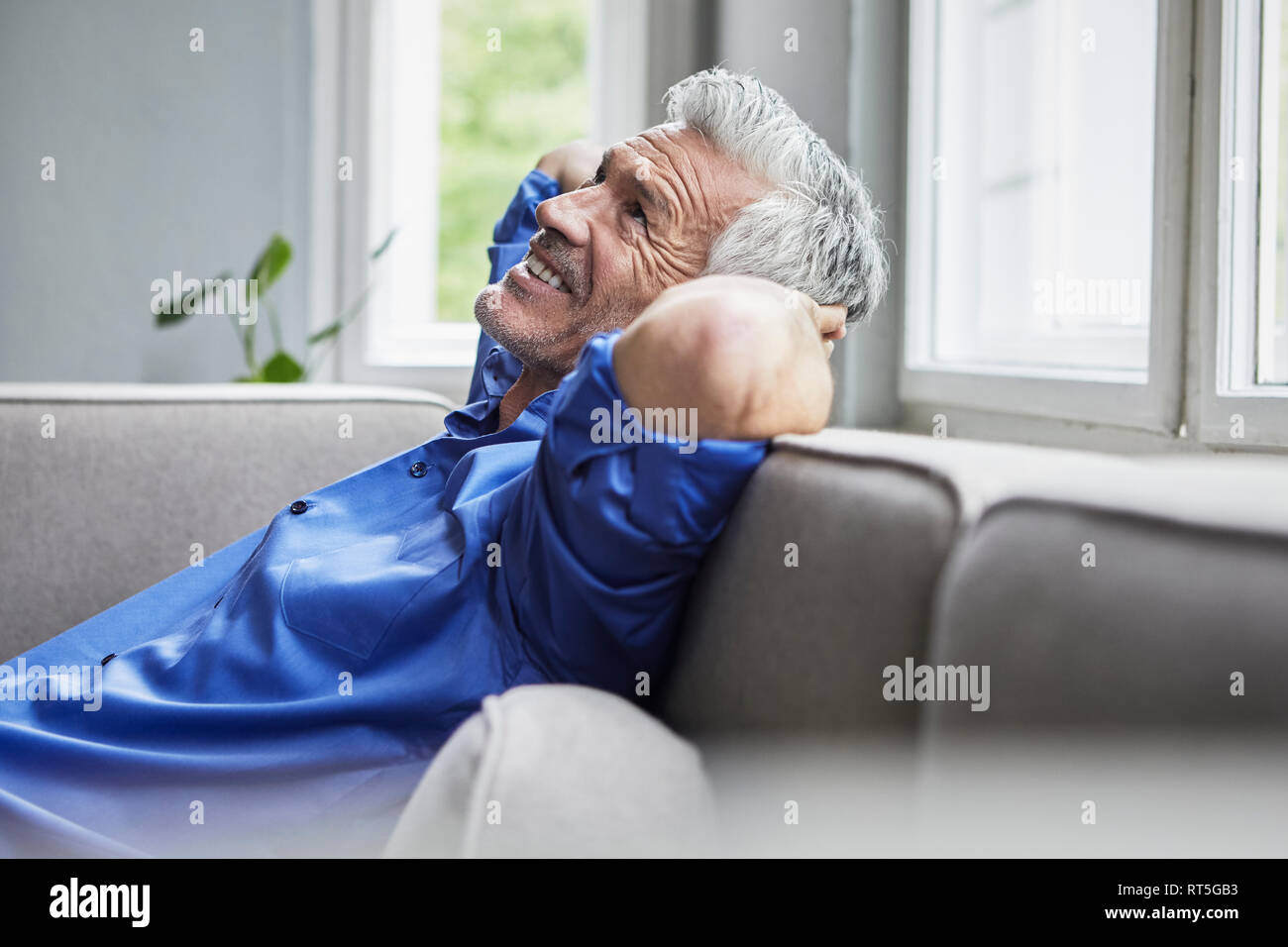 Rilassata uomo maturo seduto sul divano di casa Foto Stock