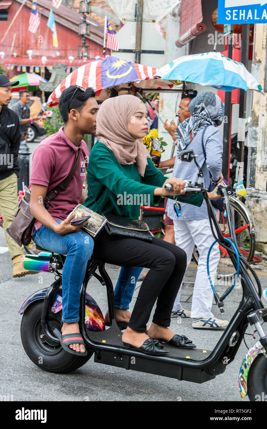 George Town, Penang, Malaysia. Giovane coppia malese a cavallo di un scooter. Foto Stock