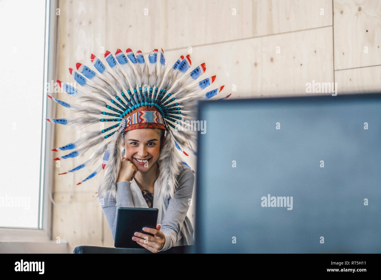 Giovane donna indossare copricapo indiano, stando in ufficio utilizzando la tavoletta digitale Foto Stock