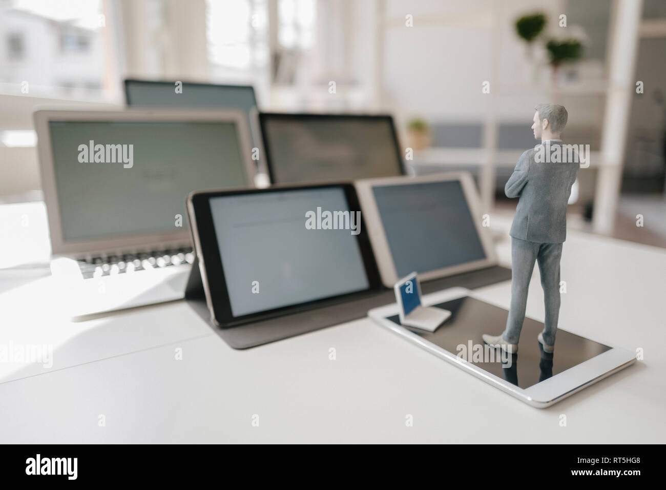 Imprenditore figurina in piedi sulla scrivania, rivolta verso i dispositivi mobili Foto Stock