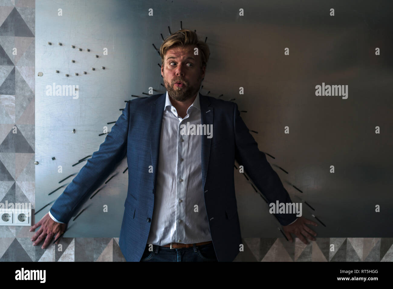 Imprenditore standiing nella sala riunioni con il dorso di un magnete a parete, incorniciato dalle frecce Foto Stock