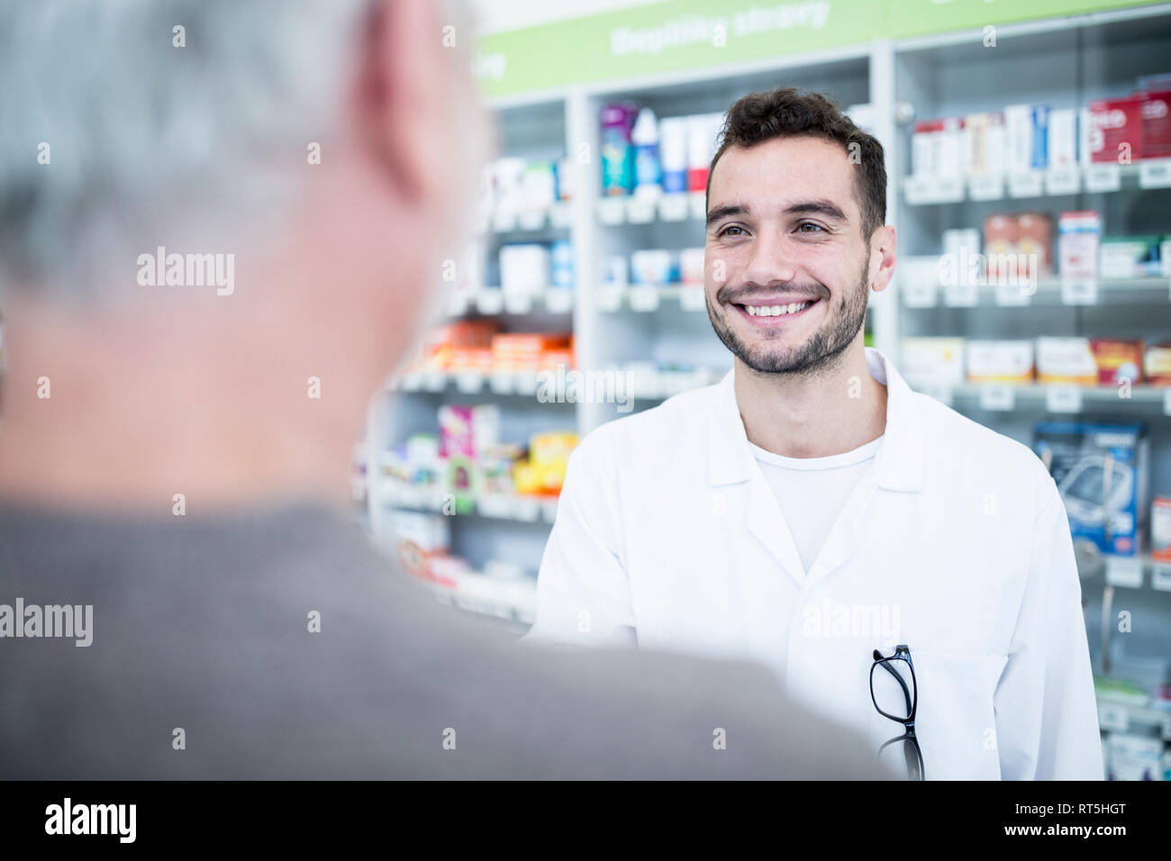 Il farmacista a sorridere al cliente in farmacia Foto Stock