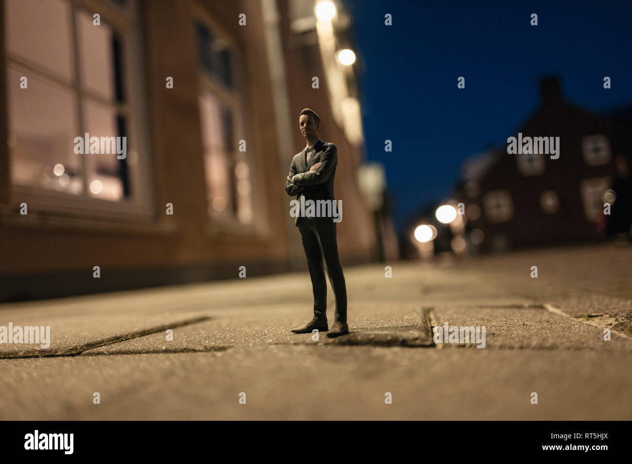 Imprenditore figurina in piedi in strada di fronte di case Foto Stock