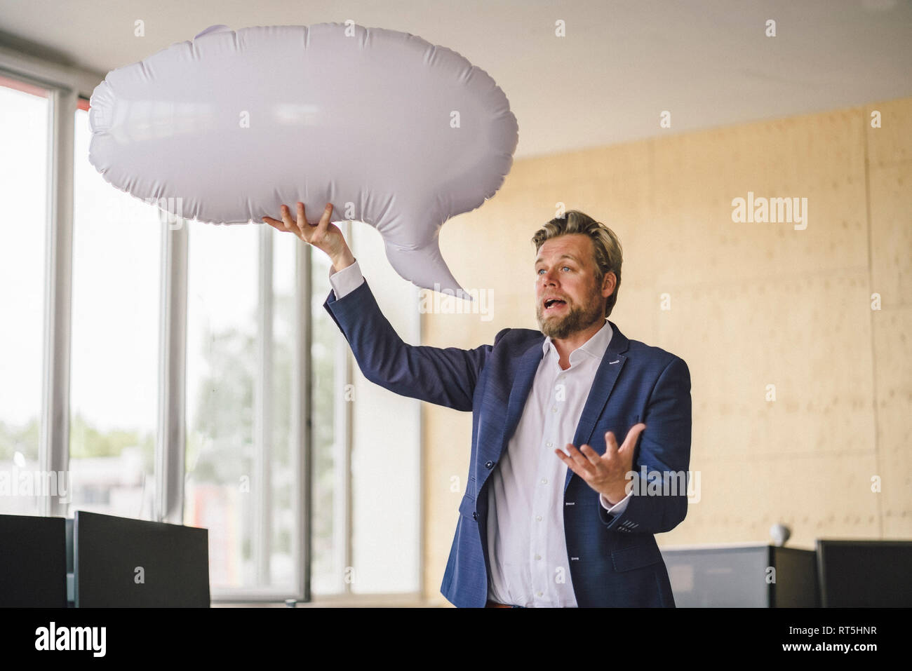 Imprenditore in piedi in ufficio, tenendo gonfiabile di discorso bolla Foto Stock