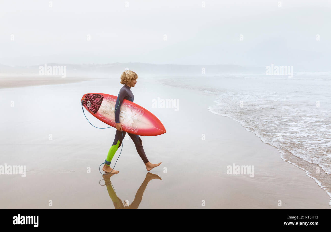 Spagna, Aviles, giovani surfer camminando verso l'acqua Foto Stock