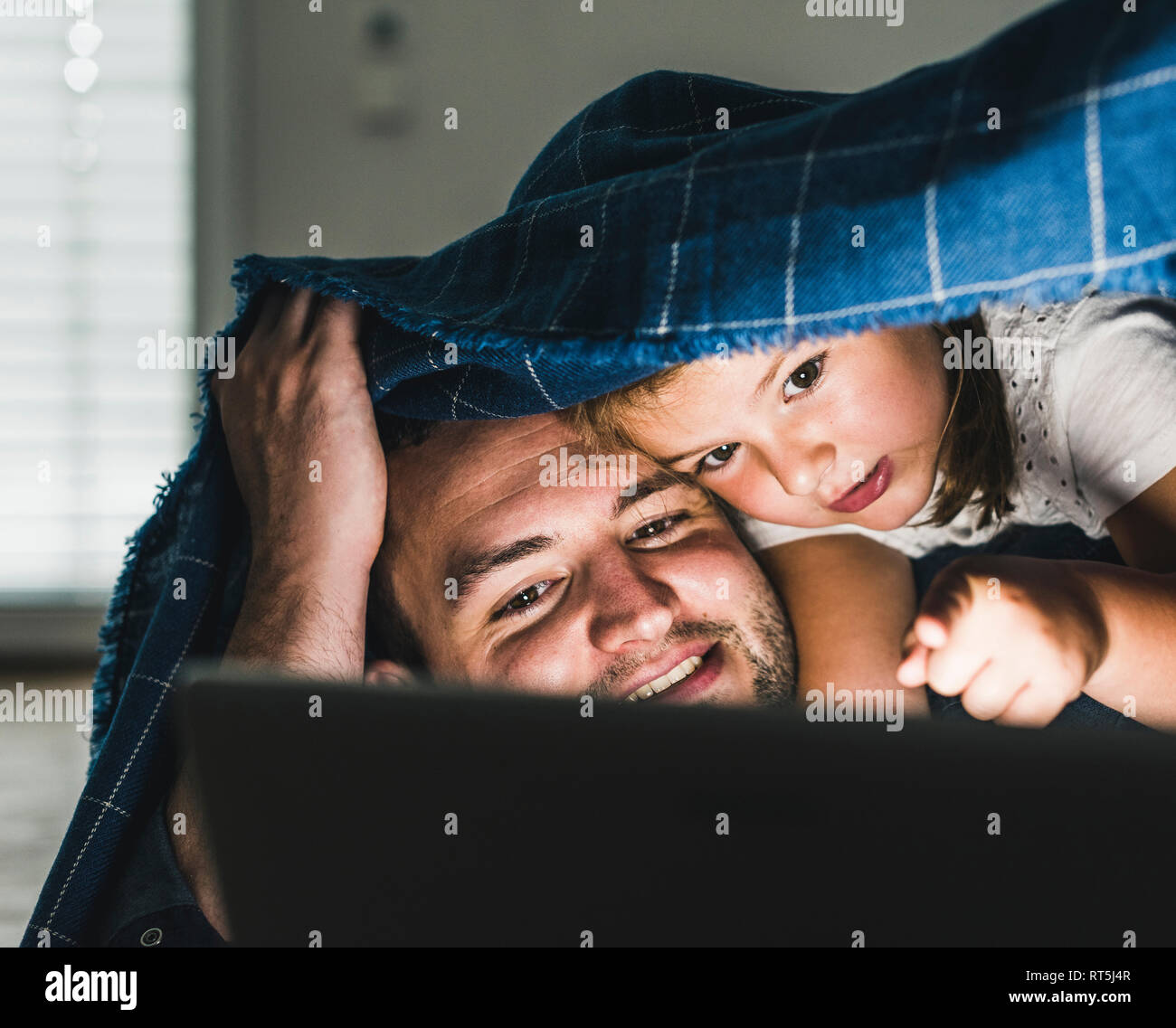 La famiglia felice si nasconde sotto coperta, la visione di film sul computer portatile Foto Stock