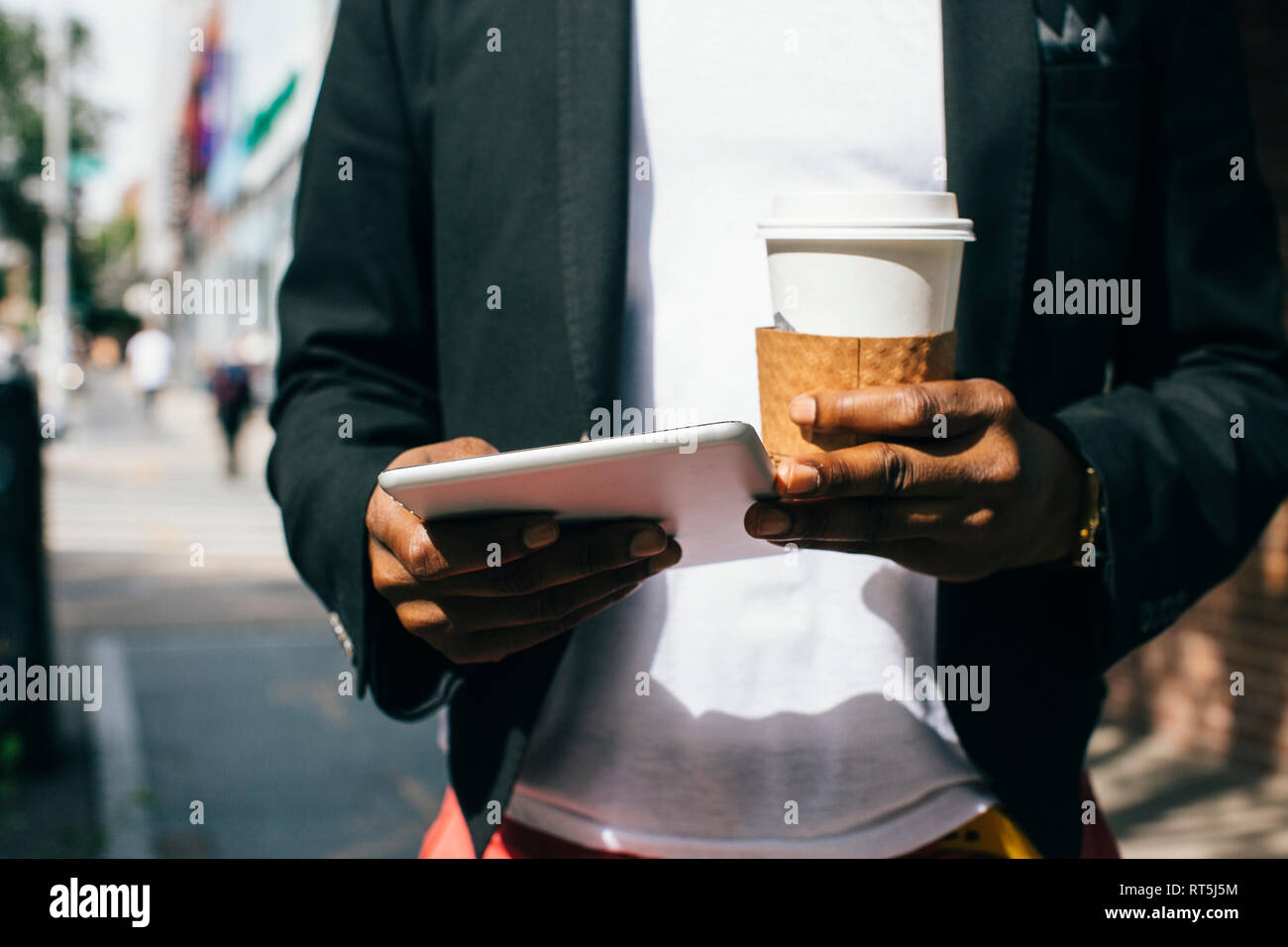 Stati Uniti d'America, New York, Brooklyn, uomo a camminare per la strada, tenendo tazza di caffè e la tavoletta digitale Foto Stock