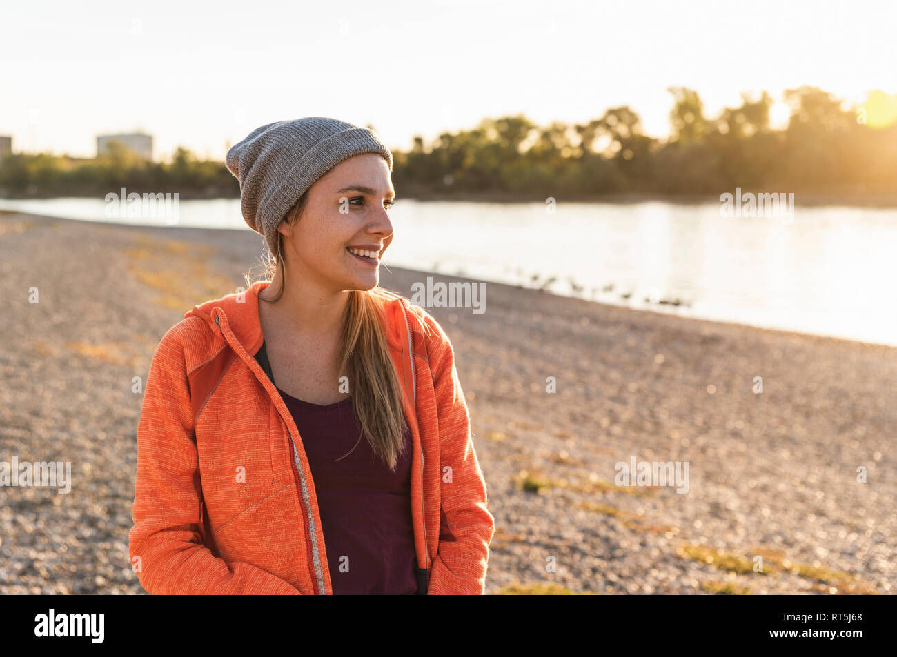 Ritratto di un giovane sportivo donna presso il fiume, weraing un beanie hat Foto Stock