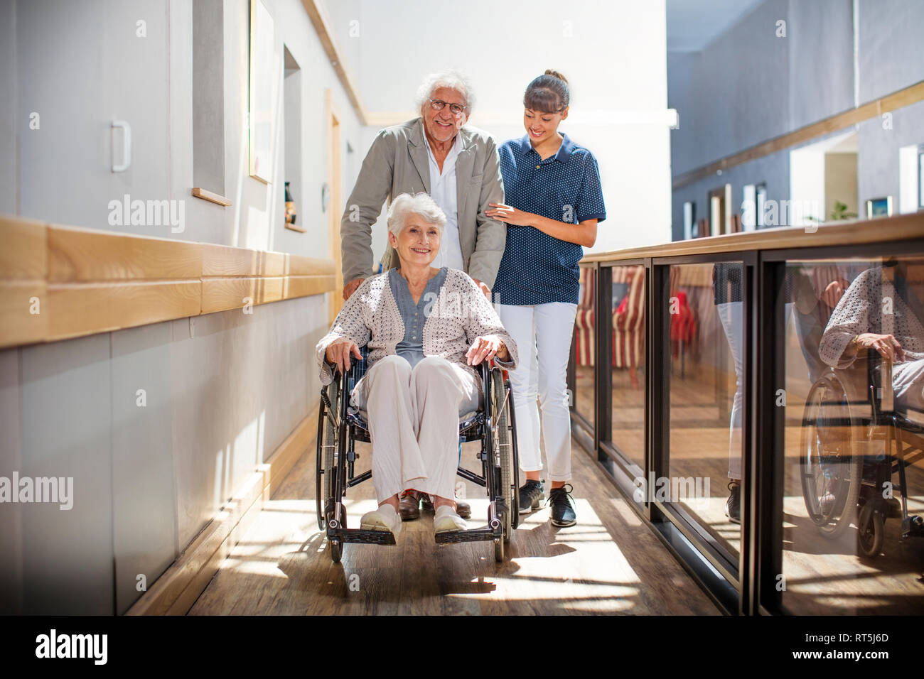 Infermiera Gereatric aiutando senior l uomo e la donna a camminare per il corridoio Foto Stock