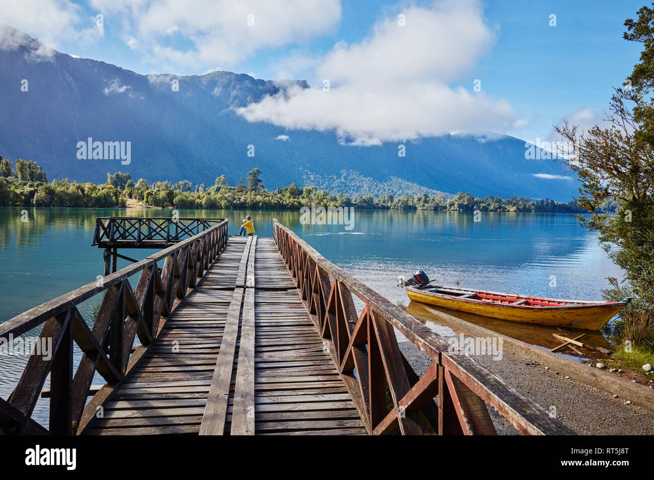 Il Cile, Chaiten, Lago Rosselot, donna seduta sul molo a distanza Foto Stock
