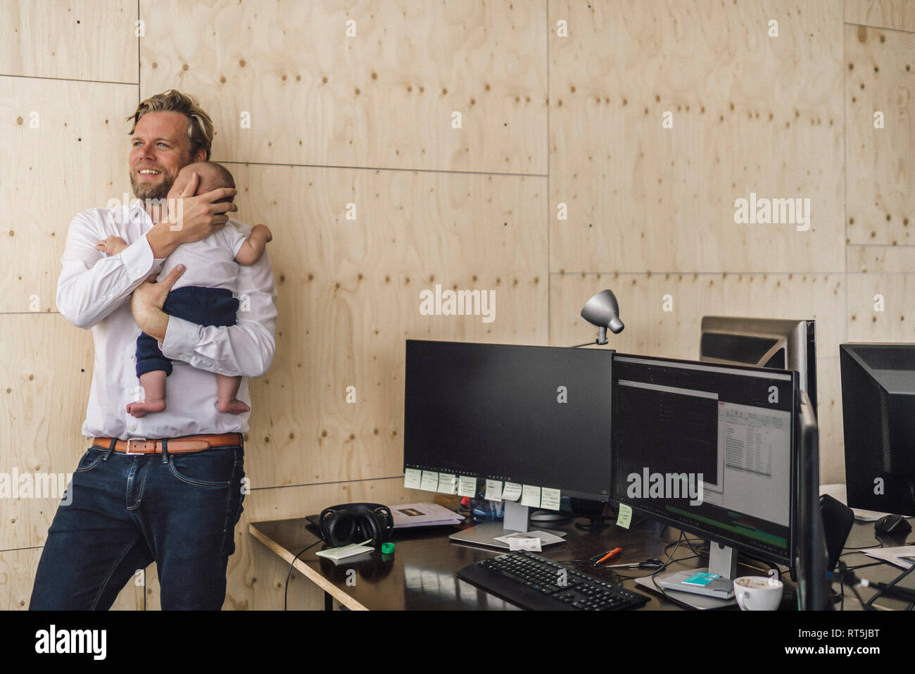 Padre di lavoro in piedi in ufficio, tenendo il suo figlio Foto Stock