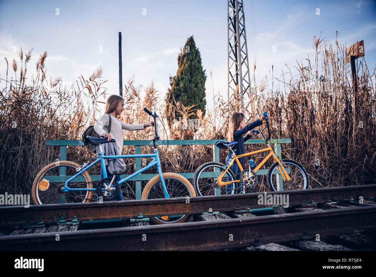 Due ragazze di camminare sulla via treno con le biciclette Foto Stock