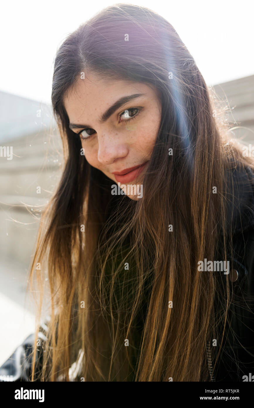 Ritratto di fiducioso giovane donna con capelli lunghi marrone all'aperto Foto Stock