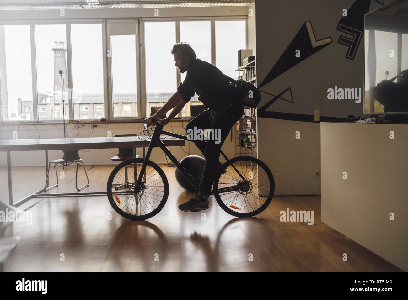 L'uomo entrando in ufficio con la sua bicicletta Foto Stock