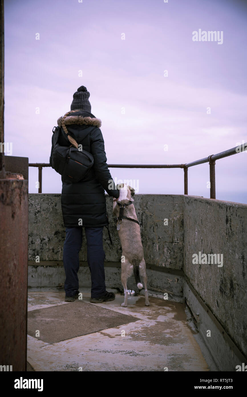 La Danimarca, a nord dello Jutland, Rubjerg Knude faro, vista posteriore della donna con il cane cercando di visualizzare al blue ora Foto Stock