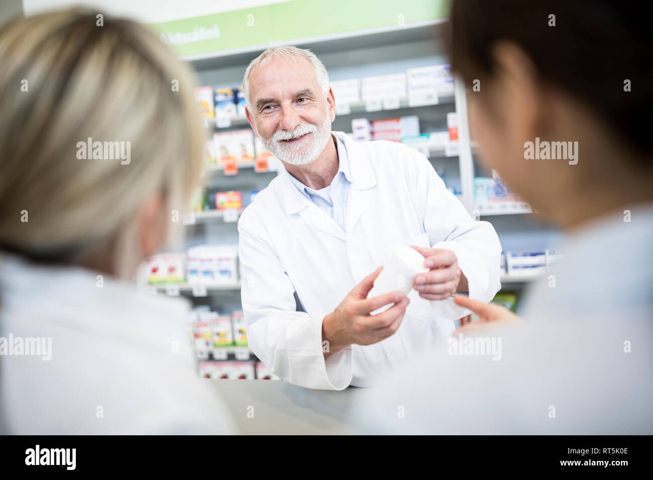 Il farmacista sorridente a due donne in farmacia Foto Stock