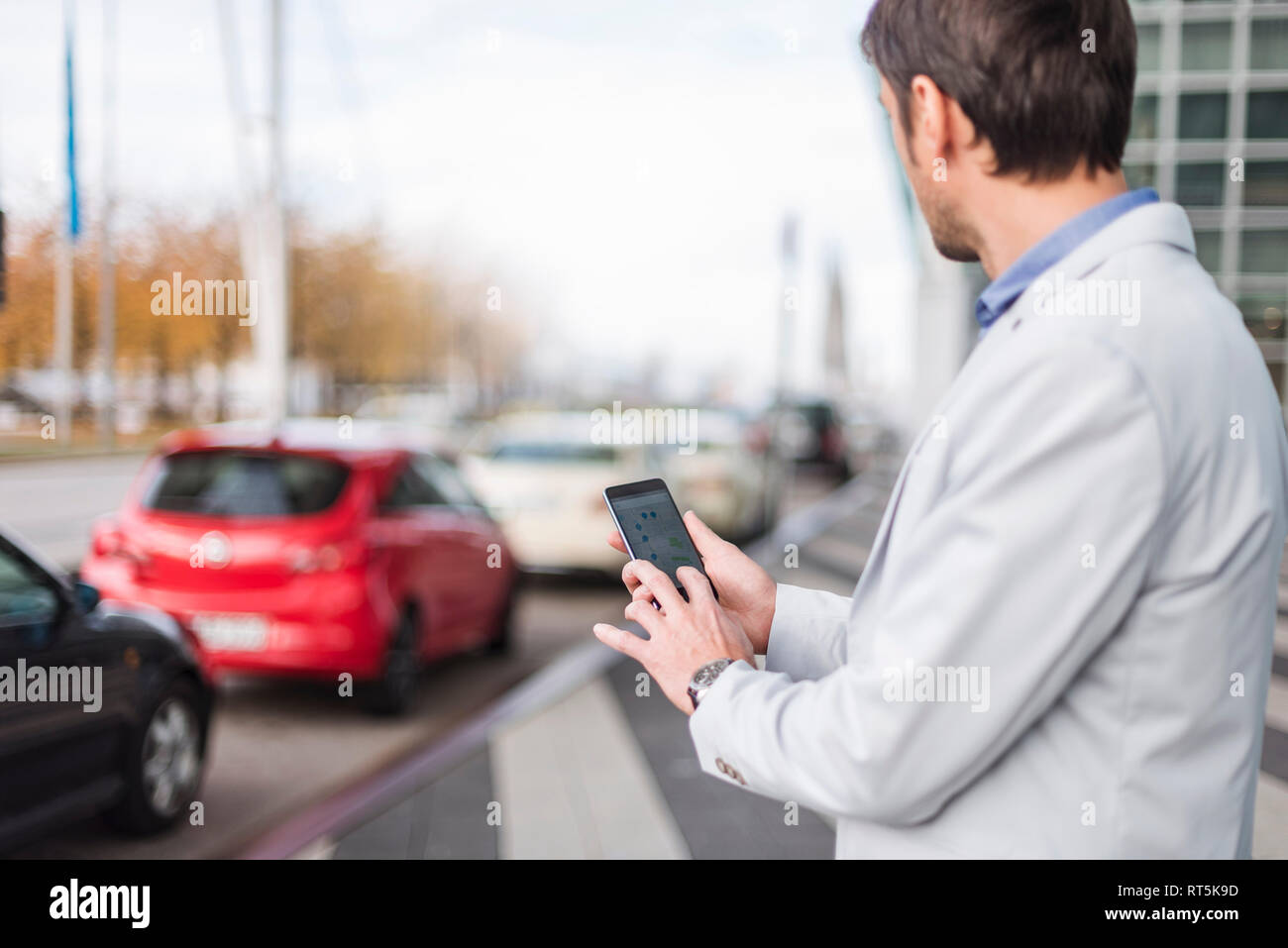 Uomo d'affari in cerca di una vettura con il suo car sharing app Foto Stock