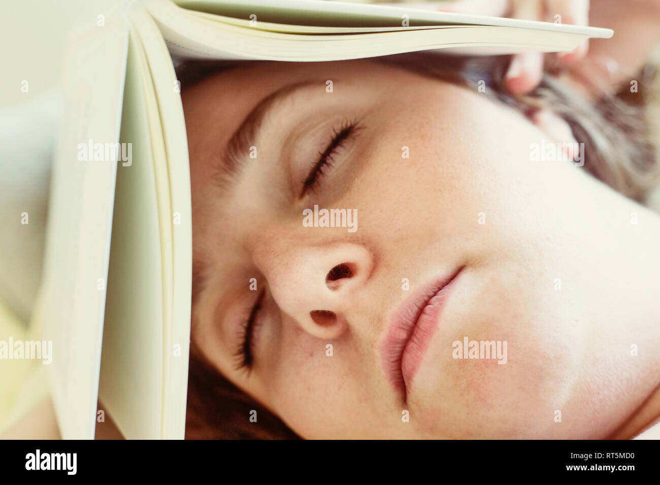 Ritratto di giovane donna che dorme con libro sulla testa, close-up Foto Stock