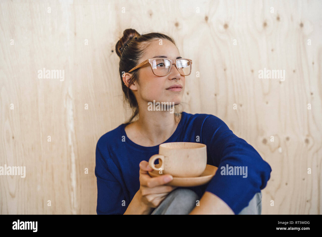 Giovane donna prendendo una pausa in ufficio, bere il caffè da una tazza di legno Foto Stock